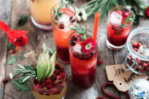 A tableful of fresh cocktails garnished for the holidays with herbs